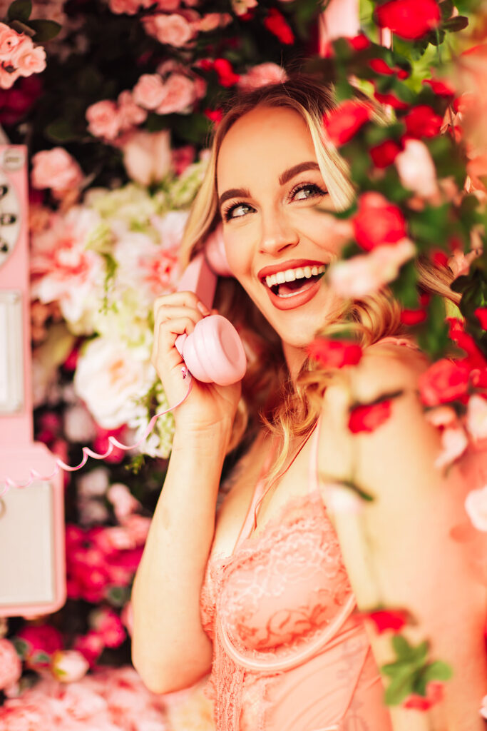 "Romantic boudoir photo in a pink London telephone booth filled with blooming flowers."
"Couple embraces in an intimate moment surrounded by pink-painted telephone booth and floral decorations."
"Soft and passionate boudoir setting with a pink London phone booth and a sea of flowers."