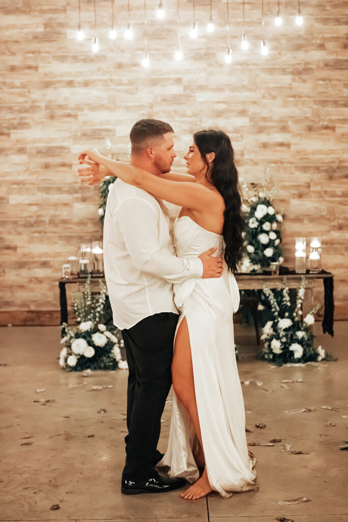 The couple sharing a tender moment during their last dance, surrounded by the warm glow of Gentry Pines.