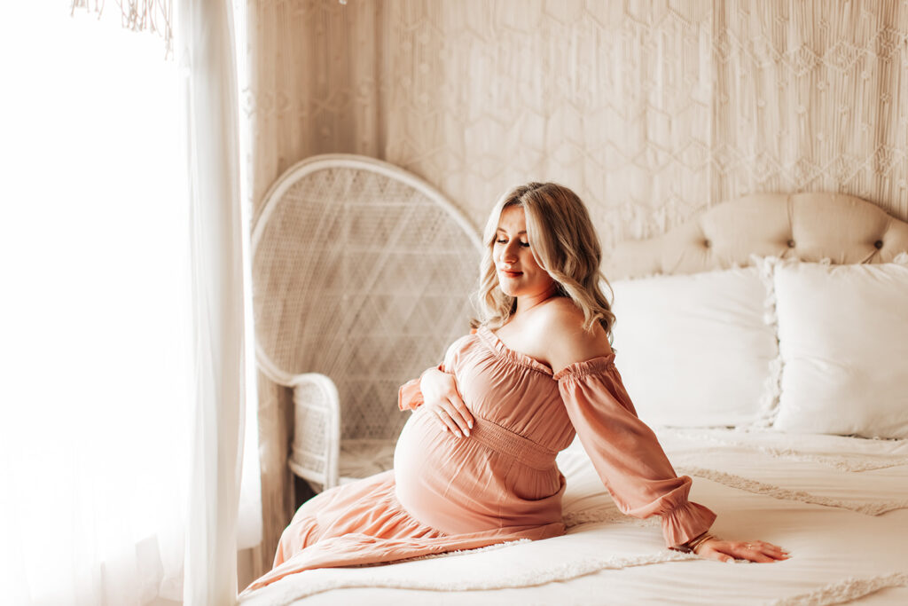 Expectant mother smiling during a studio maternity photoshoot at Wings of Glory Photography