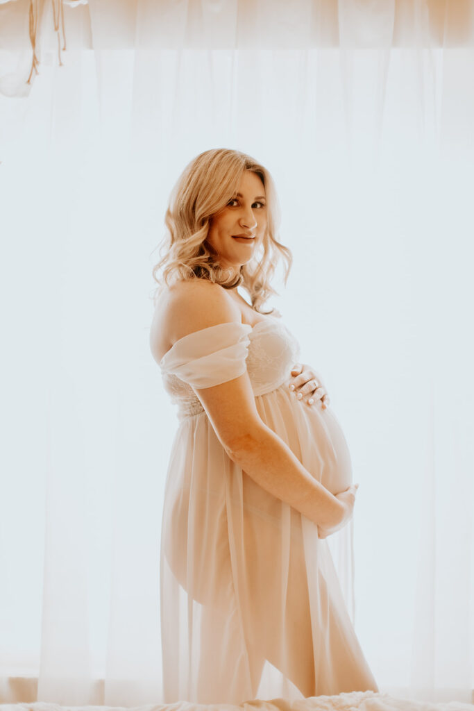 Expectant mother smiling during a studio maternity photoshoot at Wings of Glory Photography