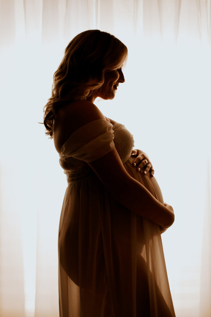 Expectant mother smiling during a studio maternity photoshoot at Wings of Glory Photography