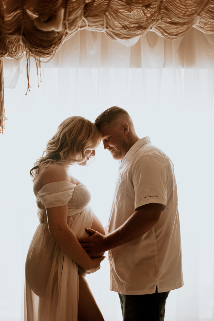 Expectant mother smiling during a studio maternity photoshoot at Wings of Glory Photography