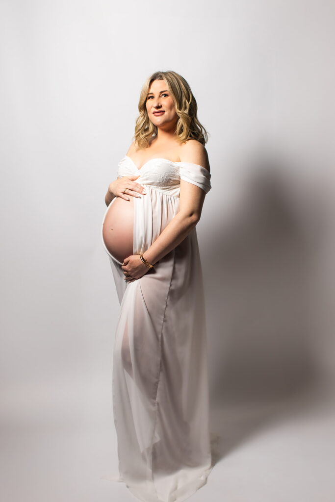 Expectant mother smiling during a studio maternity photoshoot at Wings of Glory Photography