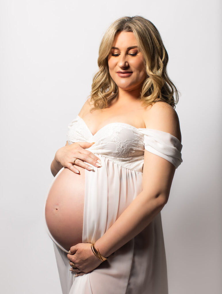 Expectant mother smiling during a studio maternity photoshoot at Wings of Glory Photography