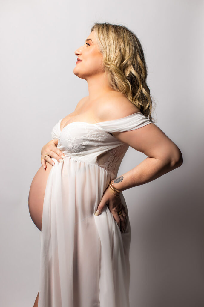 Expectant mother smiling during a studio maternity photoshoot at Wings of Glory Photography
