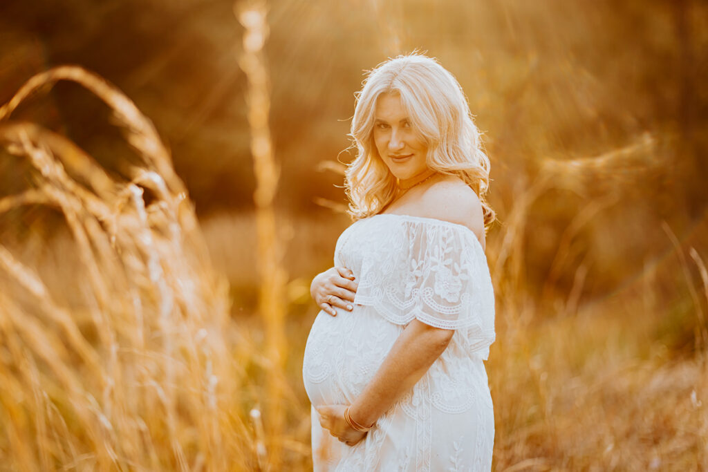 Pregnant couple walking hand in hand through a picturesque outdoor location during a maternity photoshoot with Wings of Glory Photography